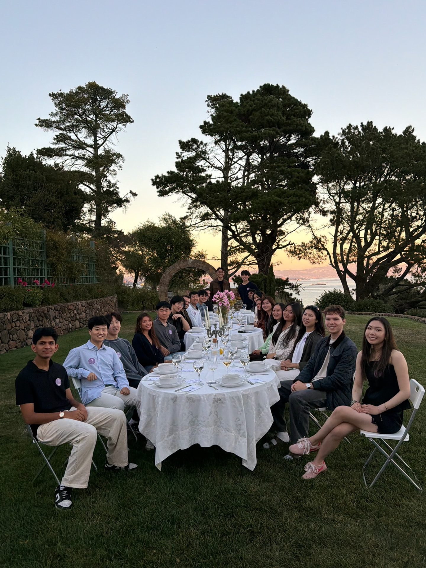 PlateTale community members gathered around an outdoor dinner table at sunset